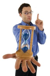 Man in blue shirt holding hourglass, emphasizing urgency for sewer repairs and plumbing services.