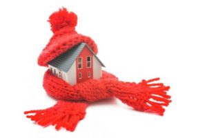 Model house wrapped in a red knitted scarf and hat, symbolizing winter insulation and home warmth.