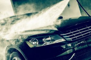 Car being washed at an automated car wash, showcasing water spray and steam, emphasizing water conservation and efficient cleaning practices.