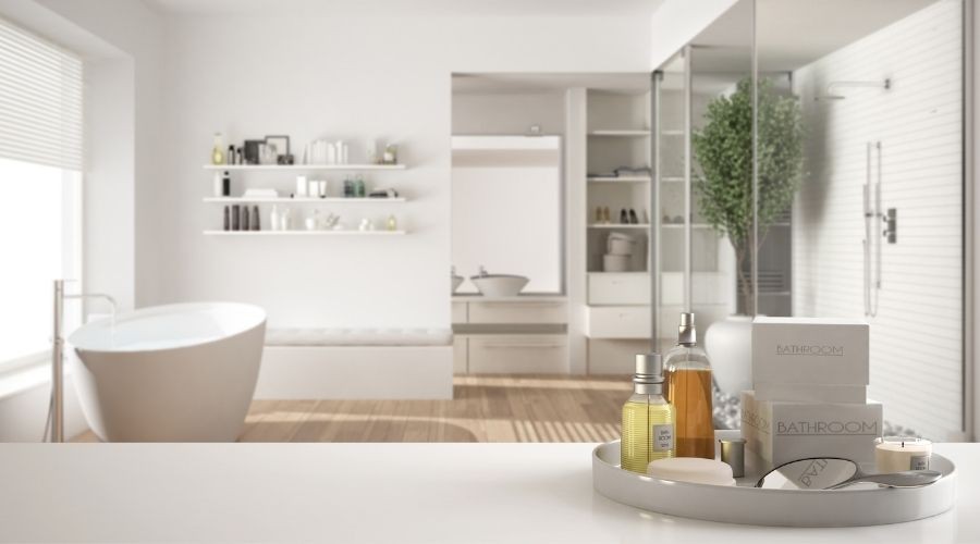Modern bathroom with a bathtub, shelf of skincare items, and natural light, highlighting Green Hills Plumbing services.