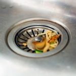 Kitchen sink drain with food scraps, highlighting waste disposal; plumbing service by Green Hills Plumbing needed.