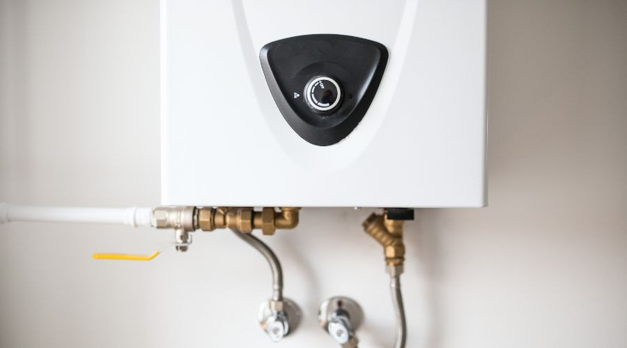 Tankless water heater with control knob and plumbing connections for efficient home utility services by Green Hills Plumbing.